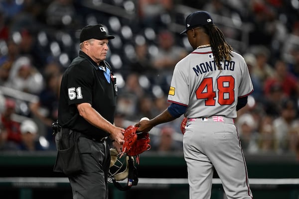 Umpire Marvin Hudson checks out Braves reliever Rafael Montero's glove.