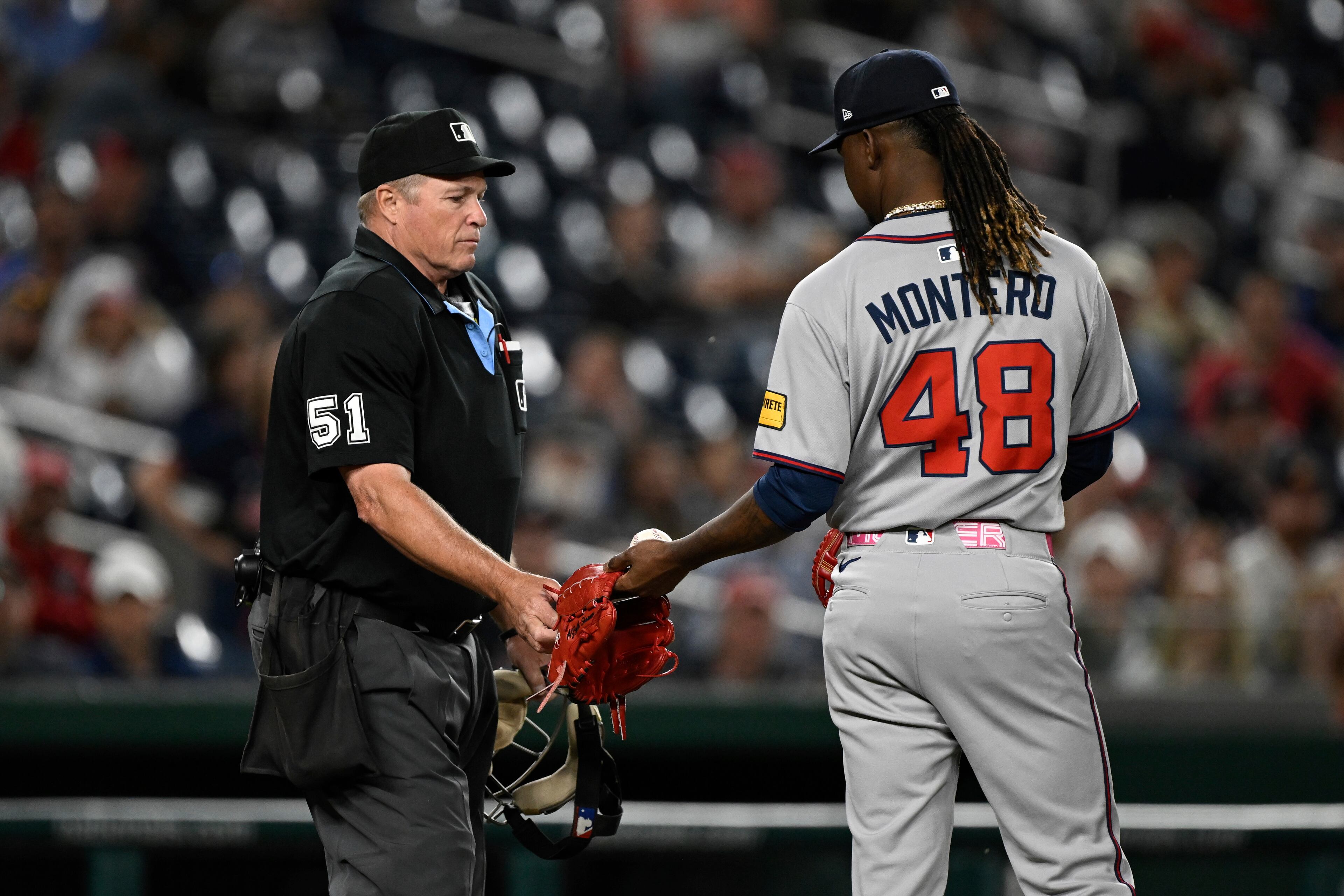 Umpire Marvin Hudson (51) takes a glove away from Atlanta Braves pitcher Rafael Montero (48) due to the two tone color of the glove during the eighth inning of a baseball game in Washington, Tuesday, May 20, 2025. (AP Photo/Terrance Williams)