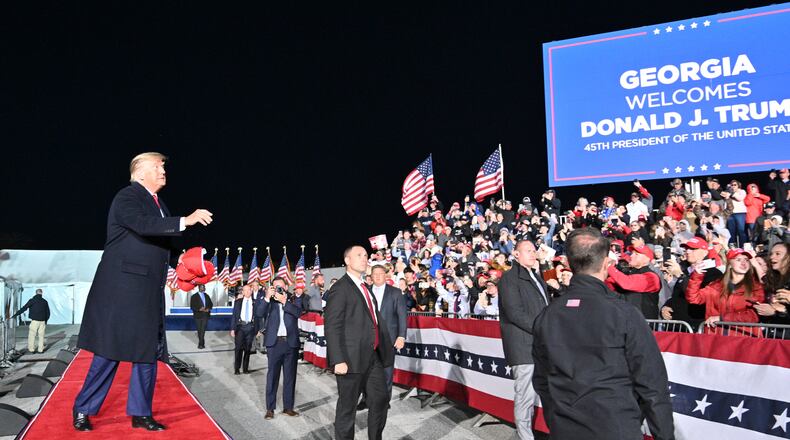 March 26, 2022 Commerce - Former former President Donald Trump throws hats as he enters the stage during a rally for Georgia GOP candidates at Banks County Dragway in Commerce on Saturday, March 26, 2022. (Hyosub Shin / Hyosub.Shin@ajc.com)