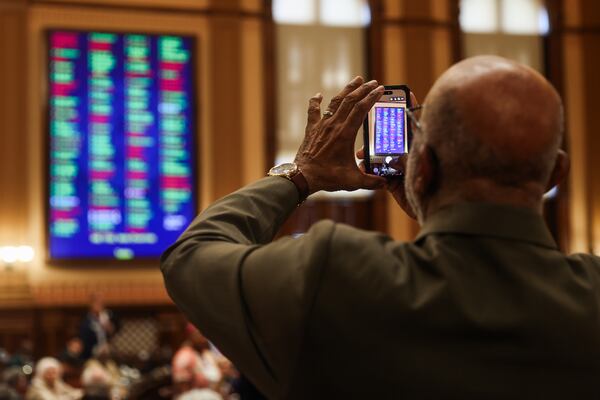A representative takes a photo of the votes for HB 1192 on the House floor as the state Legislature convenes for the fourth day of a special legislative session at the Capitol on Monday. (Abbey Cutrer/AJC)