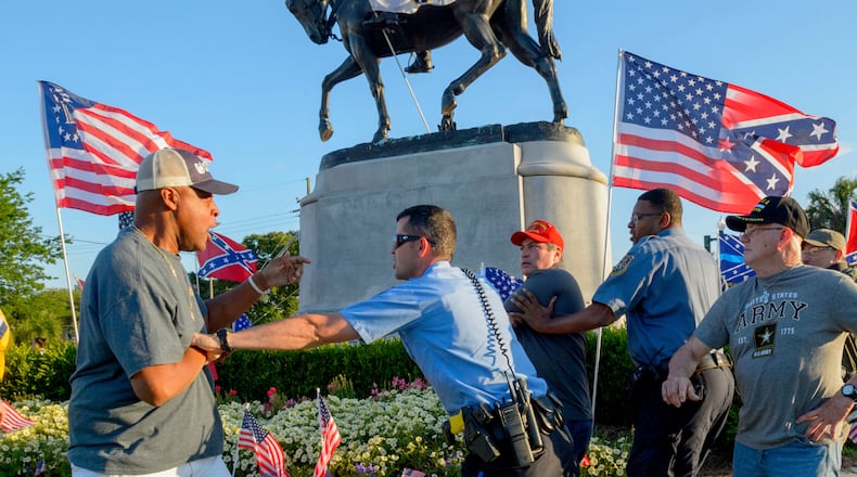New Orleans Police separate two men after the two tussled, at the Gen. P.G.T. Beauregard monument in City Park in New Orleans, La. Tuesday, May 16, 2017. Workers in New Orleans took down a Confederate monument to Gen. P.G.T. Beauregard early Wednesday. (Matthew Hinton/The Advocate via AP)