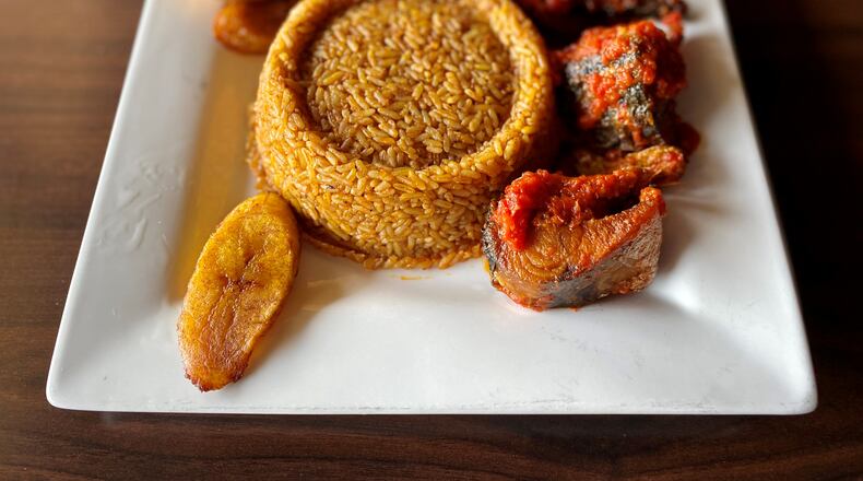 The Island Grill’s jollof rice comes with plantains and a choice of protein — in this case, fried mackerel. Wendell Brock for The Atlanta Journal-Constitution