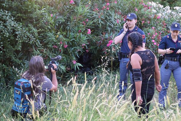 A woman films as a passerby stops by forensic police working at the site of the discovery of the body of an infant and the infant’s mother, in Rome’s Villa Pamphili park, Saturday, June 7, 2025. (Francesco Benvenuti/LaPresse via AP)