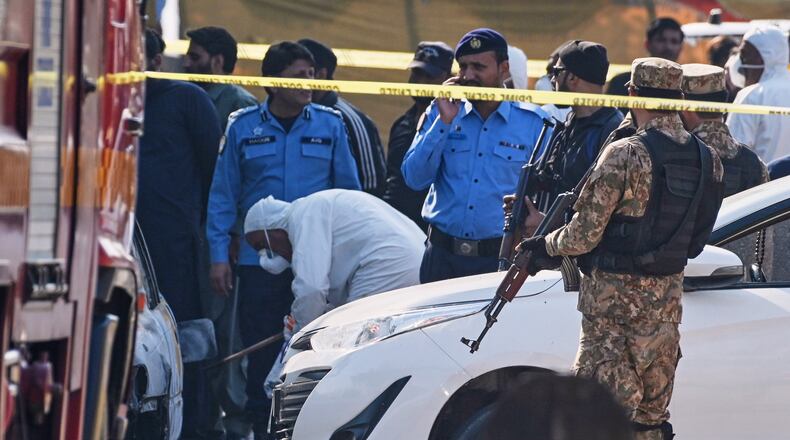 Pakistani investigators examine a damage car at the site of a suicide bombing outside the gates of a district court, in Islamabad, Pakistan, Tuesday, Nov. 11, 2025. (AP Photo/Ahsan Shahzad)
