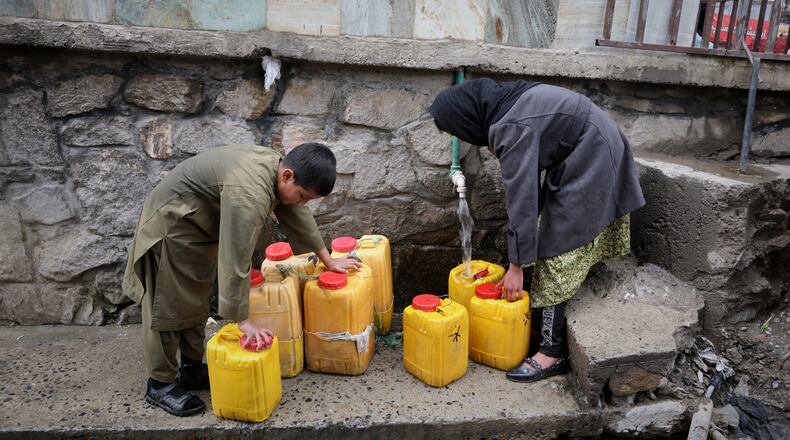 FILE - A boy and a girl collect water from a hose connected to a well at a mosque in Deh Mazang, Kabul, Afghanistan, April 2, 2026. (AP Photo/Siddiqullah Alizai, File)