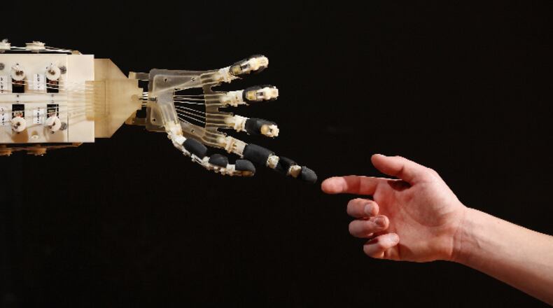 Robotics student Gildo Andreoni interacts with a Dexmart robotic hand built at the University of Bologna in the Robotville exhibition at the Science Museum on November 29, 2011 in London, England.
