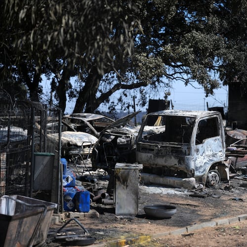 Burnt vehicles sit outside a charred house in Navas del Rey, west of Madrid, Spain, where wildfires have forced tens of thousands to be evacuated, Sunday, July 26, 2026. (AP Photo/Manu Fernandez)