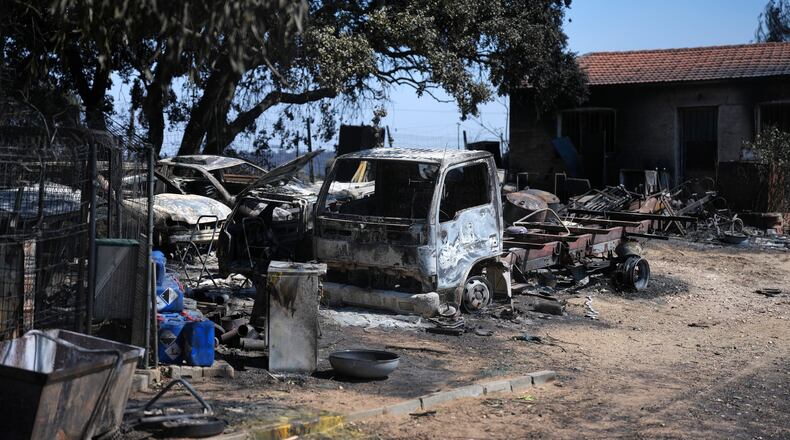 Burnt vehicles sit outside a charred house in Navas del Rey, west of Madrid, Spain, where wildfires have forced tens of thousands to be evacuated, Sunday, July 26, 2026. (AP Photo/Manu Fernandez)