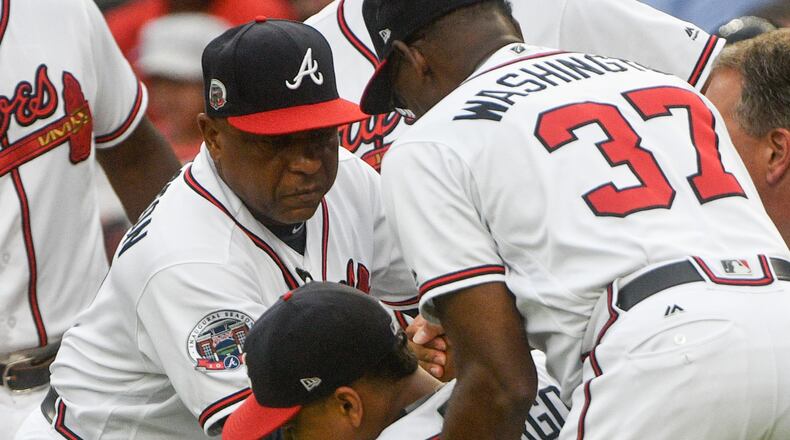 Braves rookie Johan Camargo is helped up by third base coach Ron Washington and bench coach Terry Pendleton after injuring his knee in a freak accident as he ran onto the field Aug. 8 before a game against the Phillies. (AP Photo/John Amis)