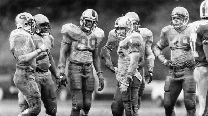 Ted Roof (center), Pat Swilling (99) and other Georgia Tech defensive players are soaked in mud during a game against Duke in 1985. Incoming Georgia Tech freshman Bruce Jordan-Swilling and Tre Swilling give Roof, now Tech’s defensive coordinator, a large amount of credit for their choosing to become Yellow Jackets. (Andy Sharp / AJC file)