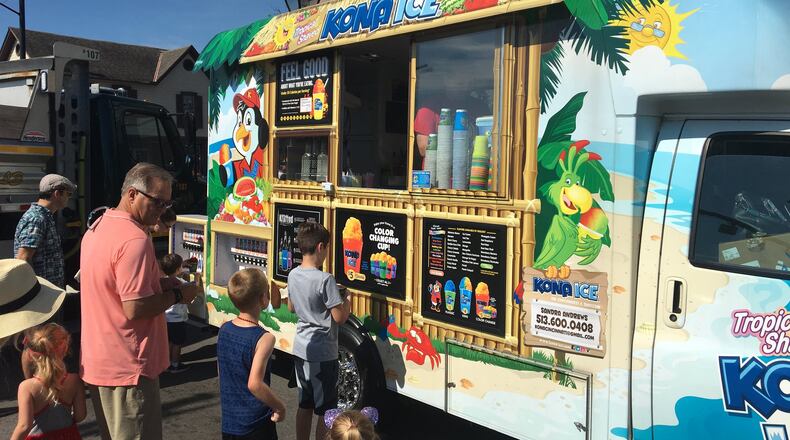 Customers line up at a Kona Ice truck at Centerville’s annual Americana Festival. Owner Sandra Andrews said the high temperatures meant the truck would sell a lot of shaved ice at the festival this year.