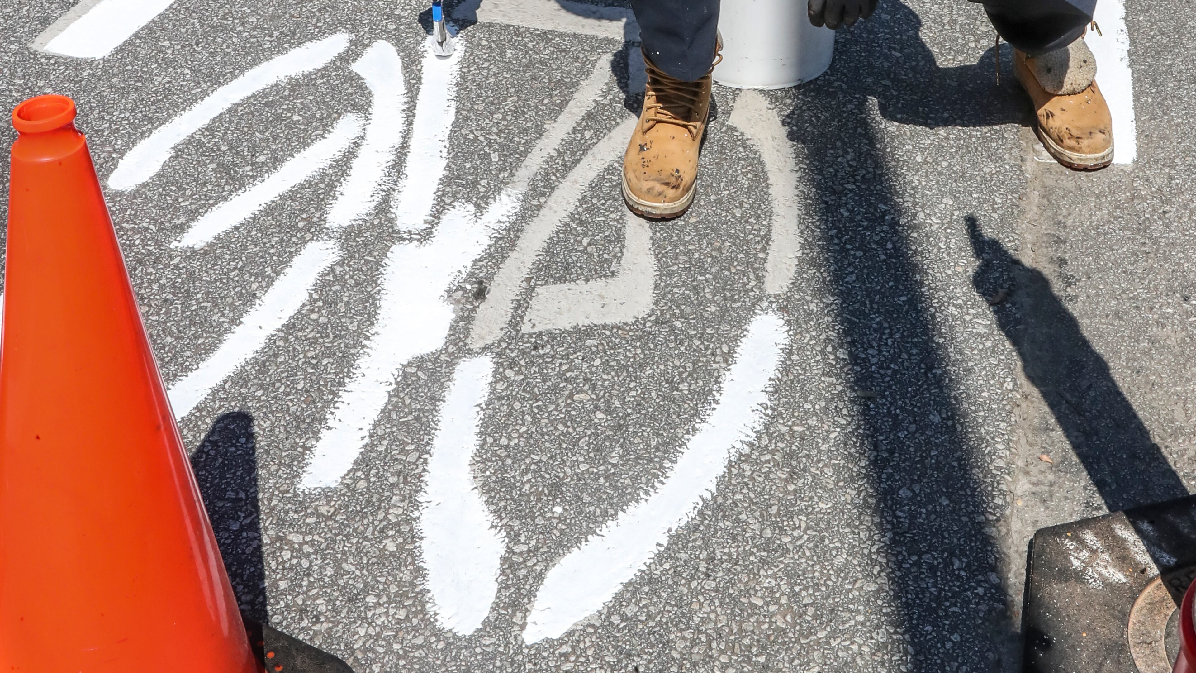 In this 2021 photo, Glenn Hickey paints a stretch of bike lanes on Ferst Drive on the campus of Georgia Tech. (John Spink/AJC)