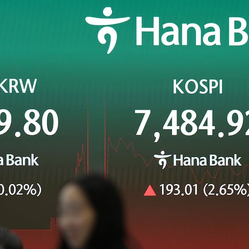A dealer walks past near the screens showing the Korea Composite Stock Price Index (KOSPI) and the foreign exchange rate between U.S. dollar and South Korean won at a dealing room of Hana Bank in Seoul, South Korea, Friday, July 10, 2026. (AP Photo/Lee Jin-man)