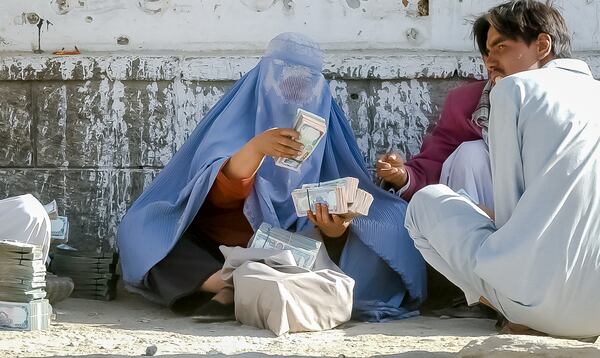 02090 KABUL, AFGHANISTAN: Money changer Shakilla counts stacks of Afghan money in Kabul's main bazaar Saturday 9/7/2002. As a woman, Shakilla is an anomaly in Kabul's money-changing market; no one asked had ever heard of a woman money changer before. (Bita Honarvar / The Atlanta Journal-Constitution)