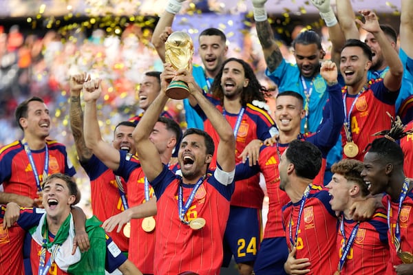 Spain's Rodri hoists the World Cup trophy surrounded by teammates. (Ashley Landis/AP)
