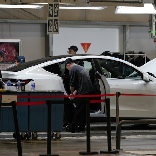 FILE - People work on the Tesla Model Y production line at the Tesla Gigafactory assembly plant during a media organized tour, in Shanghai, China, Tuesday, April 14, 2026. (AP Photo/Andy Wong, File)
