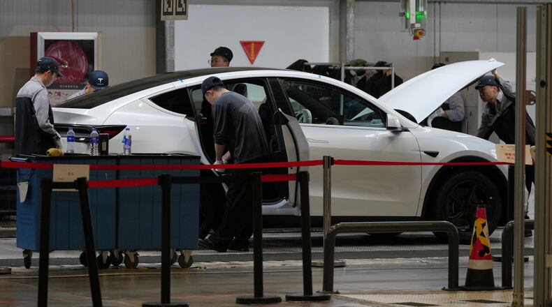 FILE - People work on the Tesla Model Y production line at the Tesla Gigafactory assembly plant during a media organized tour, in Shanghai, China, Tuesday, April 14, 2026. (AP Photo/Andy Wong, File)