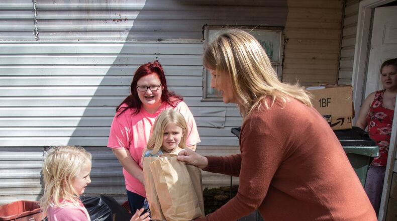 Marianne Glaser delivers lunches to Paisley Hugenschmidt as her mother, Katherine Hugenschmidt, and her sister Samantha look on Wednesday, March 25, 2020. STEVE SCHAEFER / SPECIAL TO THE AJC
