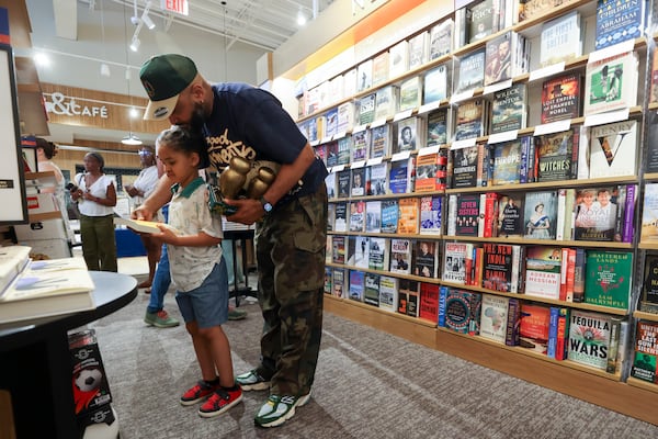 DJ Silver Knight and his son Shadeed Williams II look at a book during the Barnes & Noble grand opening at the Edgewood Retail District on Moreland Avenue, Wednesday, July 8, 2026, in Atlanta. The Edgewood Barnes & Noble offers 15,000 square feet of books, toys, games, magazines, and more. It is in the former Office Depot space next to Kroger. (Jason Getz/AJC)