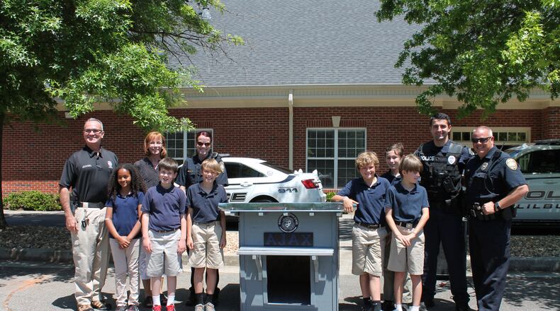 Fifth-grade students at Parkview Christian School in Lilburn pose with the doghouse they made for the Lilburn Police Department’s newest K-9, Ajax.