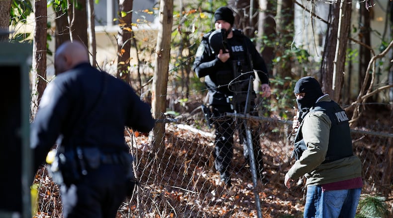 Police searched a wooded area for clues after authorities captured a second suspect who was sought after two police officers were shot in a gun battle Dec. 12, 2014, in Decatur, Ga. (AP Photo/David Goldman)
