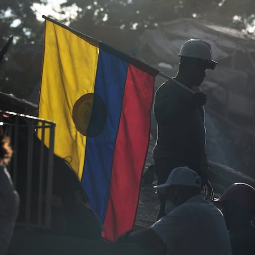A firefighter working on rescue efforts holds a Colombian flag amid the rubble three days after an earthquake struck Cali, Colombia, Thursday, Aug. 13, 2026. (AP Photo/Ivan Valencia)