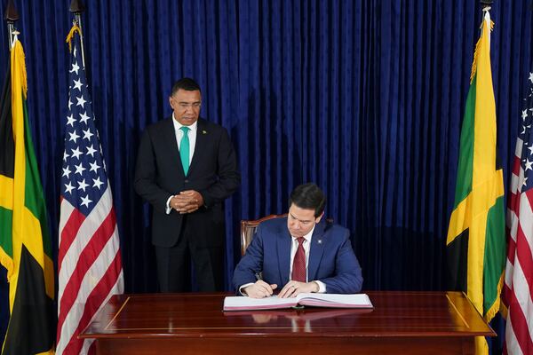 U.S. Secretary of State Marco Rubio signs a guest book next to Jamaica's Prime Minister Andrew Holness in Kingston, Jamaica, Wednesday, March 26, 2025. (Nathan Howard/Pool Photo via AP)