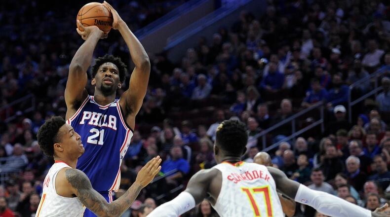 Philadelphia 76ers' Joel Embiid (21) takes a shot over Atlanta Hawks' John Collins (20) and Atlanta Hawks' Dennis Schroder (17) during the first half of an NBA basketball game, Wednesday, Nov. 1, 2017, in Philadelphia. (AP Photo/Michael Perez)