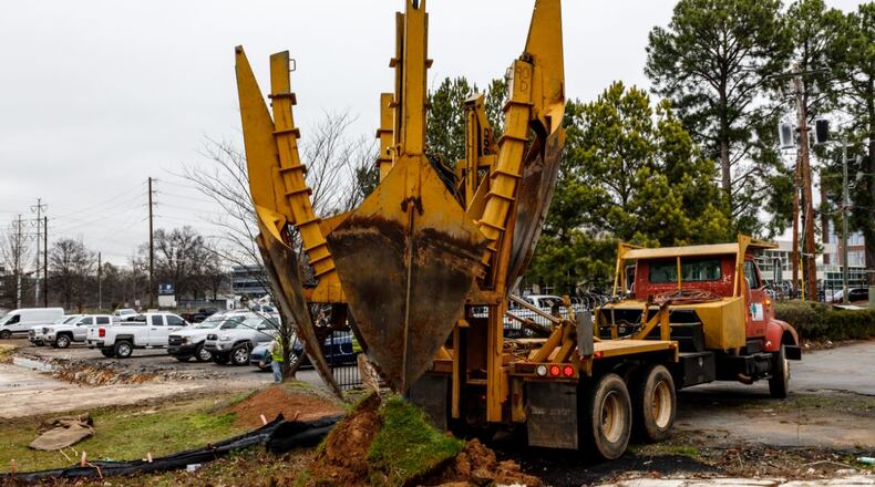 Crews remove trees on the campus before relocating them.
