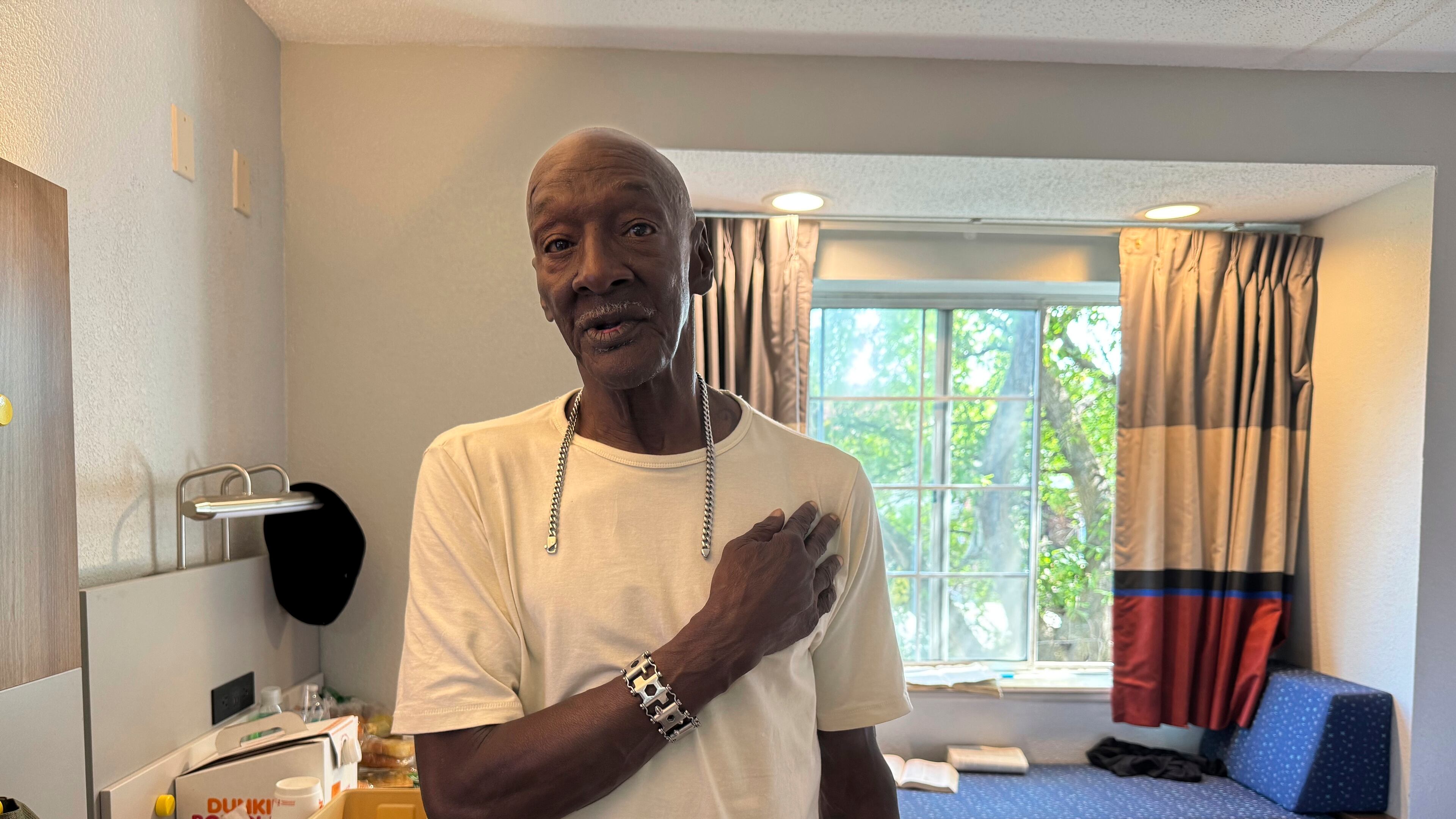Allen Hall, 71, poses for a photo in his room at a hotel in Atlanta, Wednesday, July 23, 2025, with a bracelet and chain given to him by Cornelius Taylor, who died after he was crushed by a bulldozer at a homeless encampment in January. (AP Photo/Charlotte Kramon)