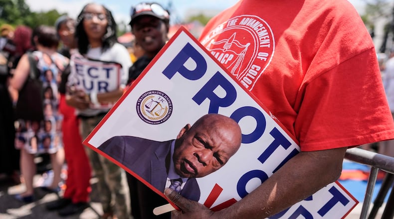 A protestor holds a sign of the late Georgia Congressman John Lewis during a voting rally, Saturday, May 16, 2026, in Montgomery, Ala. (Mike Stewart/AP)
