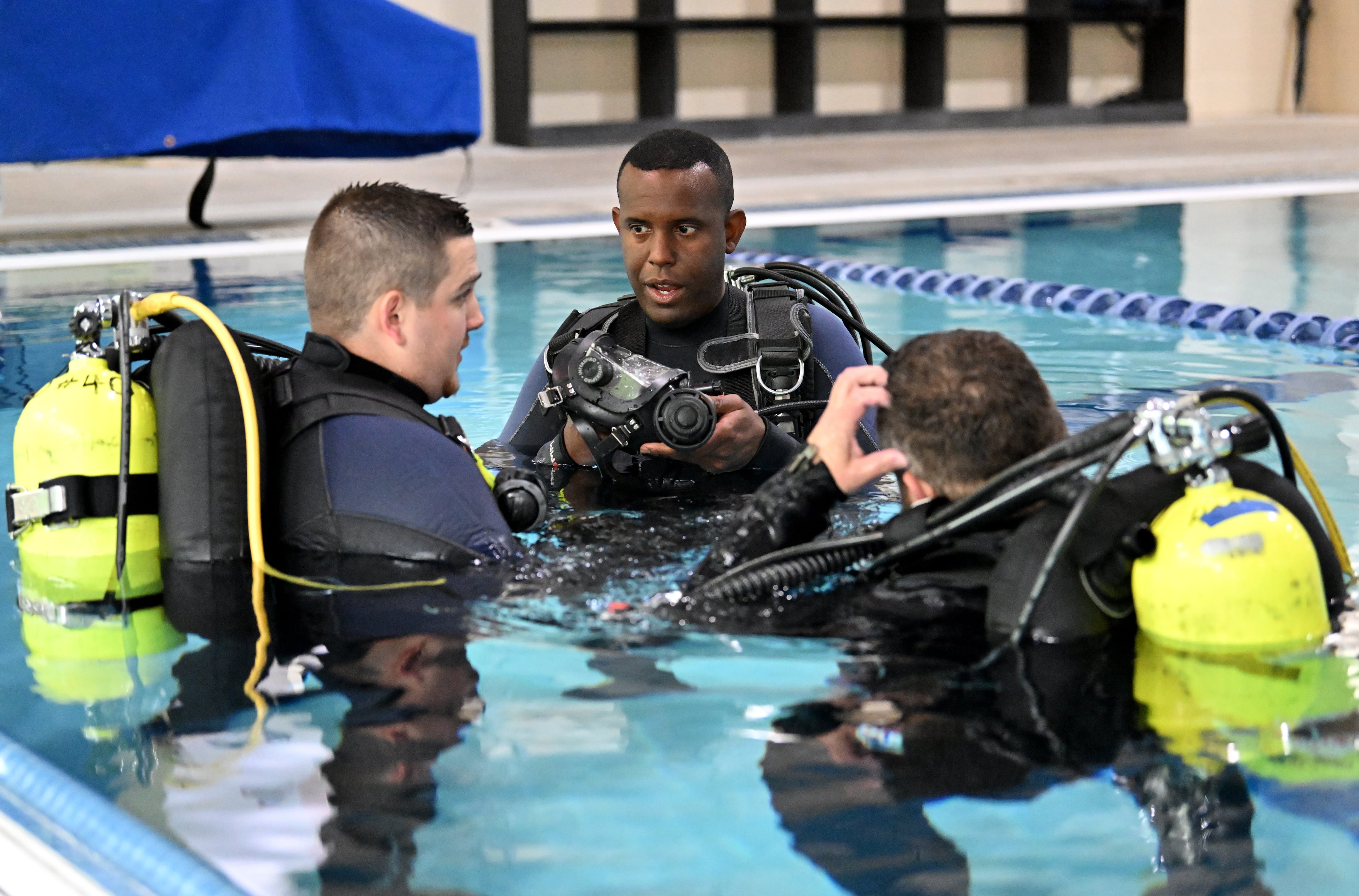 Anthony Oliver (center) works with Tyler Guthrie (left) and Michael Mitchell as they prepare for their next dives. (Hyosub Shin / AJC)