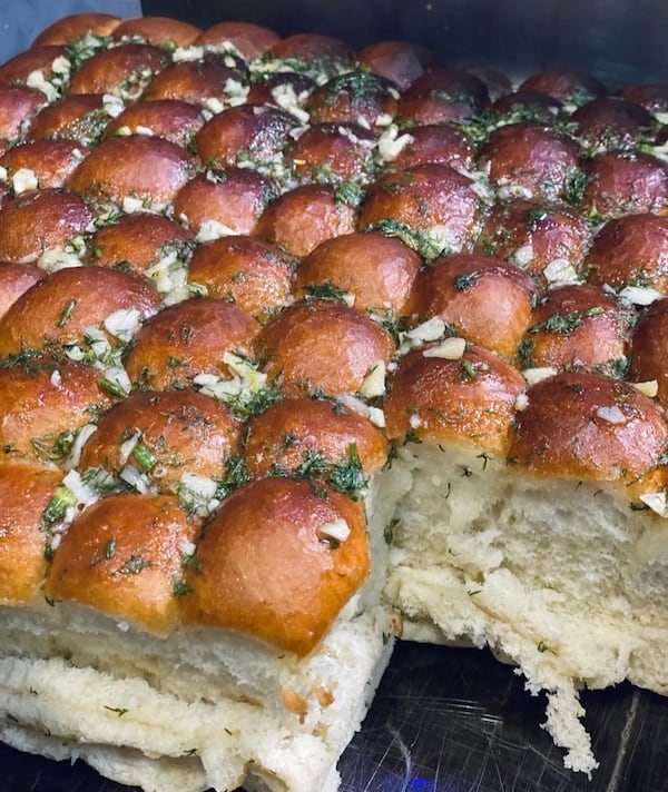 A close-up shot of numerous tall, rectangular buns. Called "pampushki," they look like a flat of Hawaiian rolls, but these are sprinkled with savory herbs.
