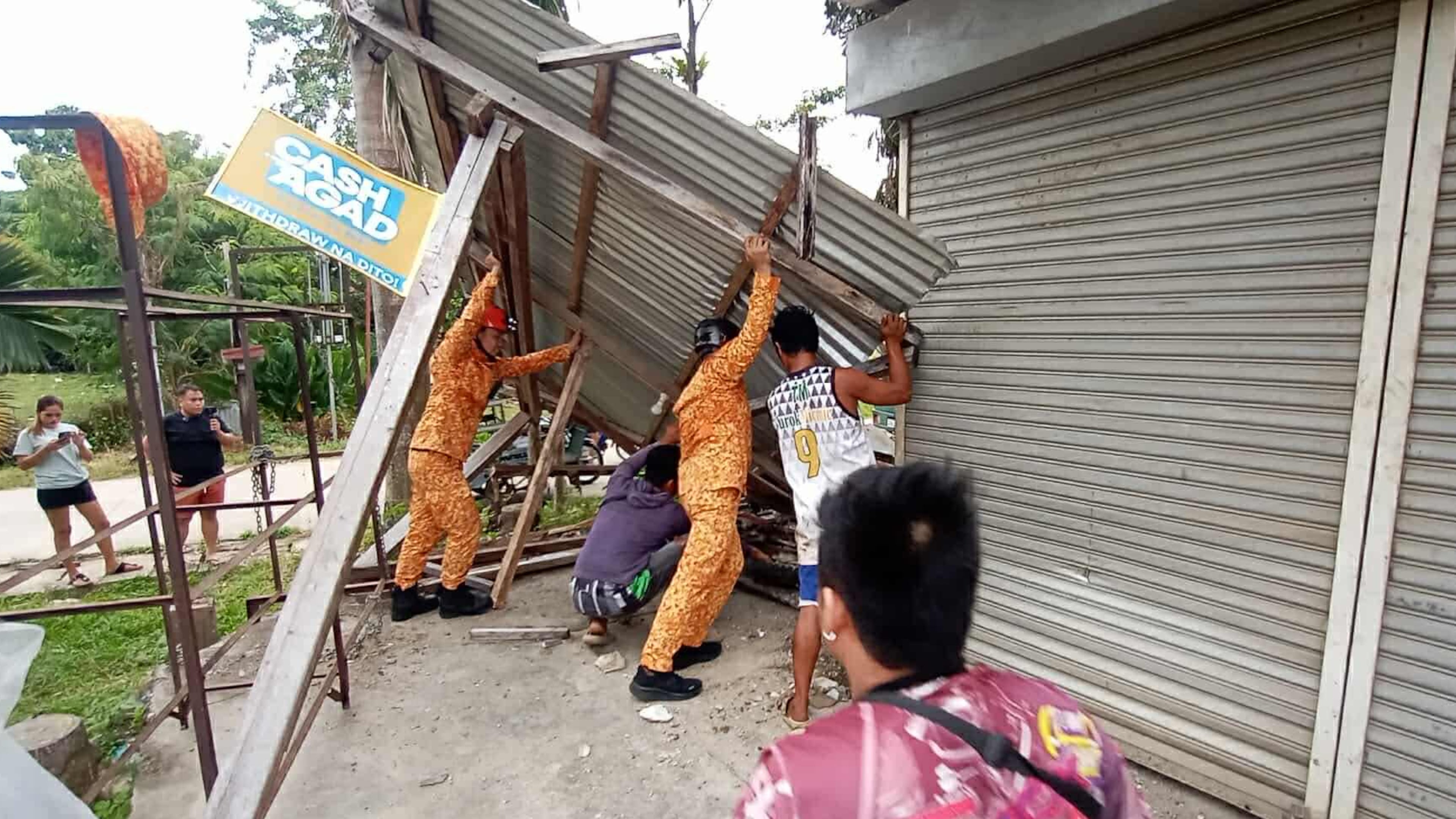 In this photo provided by the Bureau of Fire Protection, firefighters and residents hold on a toppled structure following a strong earthquake in Davao Oriental province, southern Philippines on Friday Oct. 10, 2025. (Bureau of Fire Protection via AP)