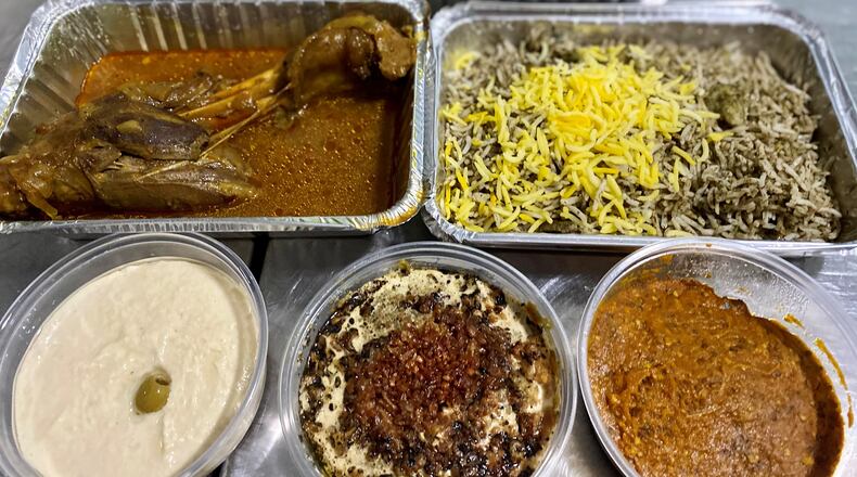 This takeout feast from Taaj Kabob & Grill includes: in the back, Shirazi salad and beef and chicken koobideh kebobs; in the middle, lamb shank and baghali polo; and up front, hummus, kashk badenjoon and mirza ghasemi. Wendell Brock for The Atlanta Journal-Constitution