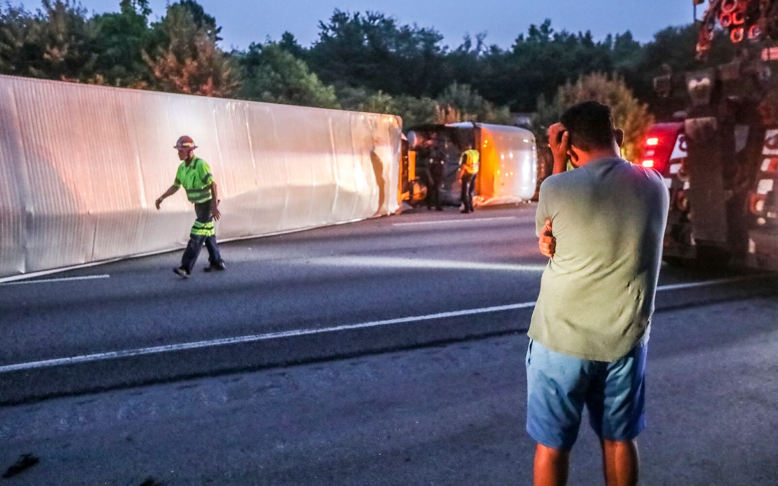 The driver of a tractor-trailer (right) appears to gather his thoughts after his rig overturned, causing a major traffic backup for Atlanta commuters. Like most days ending in Y in Atlanta, commuters were met with upheaval on the interstates Friday morning, June 23, 2023. On I-285 this toppled tractor-trailer carrying butter caused major delays for those trying to get to Hartsfield-Jackson International Airport. (John Spink / John.Spink@ajc.com)

