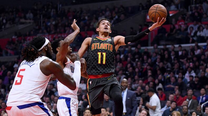 Trae Young of the Atlanta Hawks scores on a layup past Shai Gilgeous-Alexander and Montrezl Harrell of the LA Clippers during the first half at Staples Center on January 28, 2019 in Los Angeles, California. (Photo by Harry How/Getty Images)