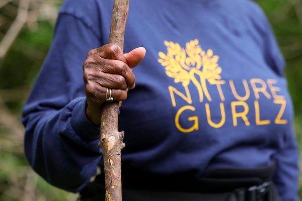A member of the Nature Gurlz holds a walking stick as they take a rest at the halfway point on their weekly morning walk along the trails at Cascade Springs Nature Preserve on April 22, 2025, in Atlanta. (Jason Getz/AJC)