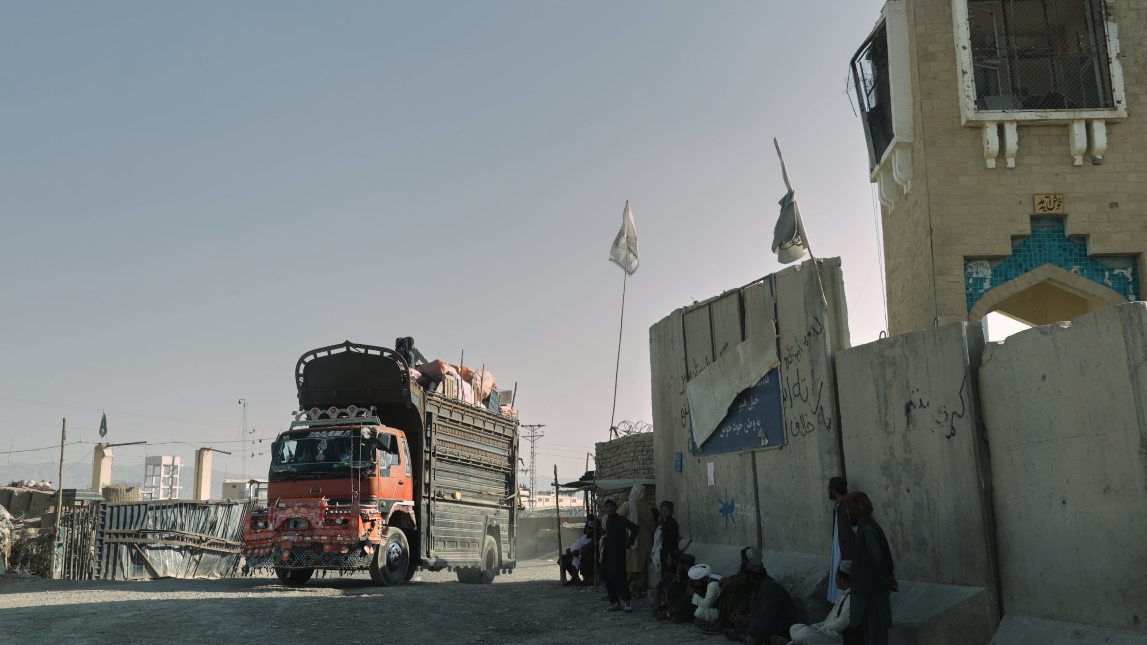 People wait near the closed gate at the Spin Boldak border crossing with Pakistan, after the border was shut for nearly two weeks following clashes between Afghan and Pakistani forces, in Kandahar province, Afghanistan, Thursday, Oct. 23, 2025. (AP Photo/Sibghatullah)
