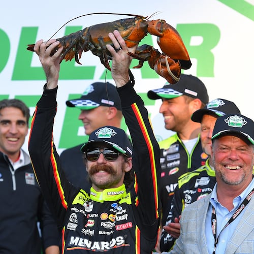 Ryan Blaney, center front, displays a lobster, a Victory Lane tradition at New Hampshire Motor Speedway, after winning a NASCAR Cup Series auto race, Sunday, Aug. 23, 2026, at the speedway in Loudon, N.H., as David McGrath, right, executive vice president and general manager of the speedway looks on. (AP Photo/Steven Senne)