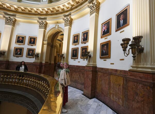 A woman takes a photograph of the empty spot where the portrait of President Donald Trump was placed after the picture, which was part of a display of all of the country's chief executives, was removed from the wall of the rotunda in the State Capitol following complaints about the likeness from Trump Tuesday, March 25, 2025, in Denver. (AP Photo/David Zalubowski)