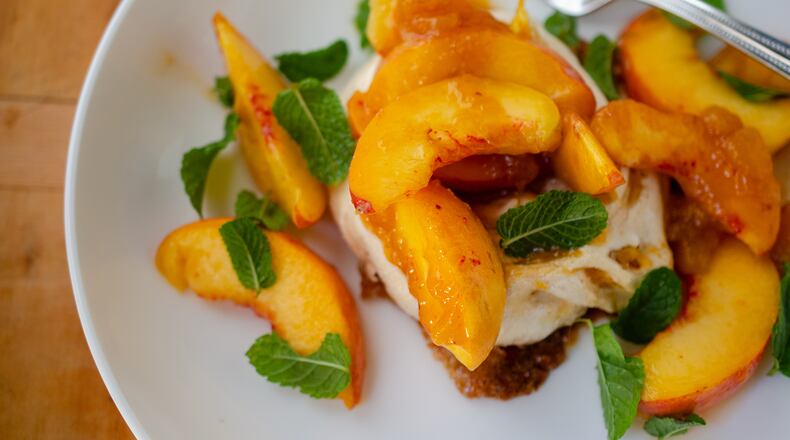 A mini peach jam-flavored pavlova topped with fresh peaches and zesty mint makes an elegant and easy summer dessert. (Virginia Willis for The Atlanta Journal-Constitution)