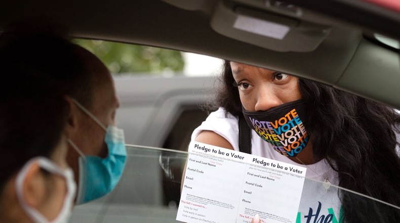 Kenisha Fray hands out Pledge To Be A Voter cards during a drive-thru food giveaway at The Home Depot Backyard Saturday, September 26, 2020. Event volunteers helped provide food and groceries to an estimated 2,500 attendees and prepared them to cast their ballots in November. STEVE SCHAEFER / SPECIAL TO THE AJC