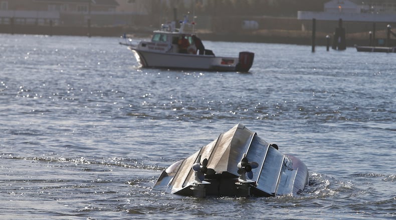 A Fire Rescue vessel passes a Coast Guard vessel that has overturned Thursday, Feb. 25, 2016, in the Queens borough of New York. Authorities say the Coast Guard vessel overturned while assisting a fishing boat that ran aground in an inlet off New York City. (AP Photo/Frank Franklin II)