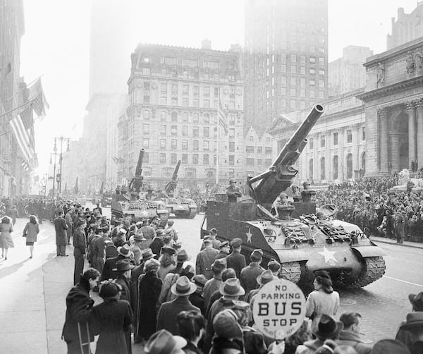 FILE - Soldiers stand at attention in their vehicles which carry 8-inch Howitzers, during the Victory Parade of the 82nd Airborne Division on Fifth Avenue in New York, Jan. 12, 1946. The parade is passing the reviewing stand in front of the Public Library, right. (AP Photo/Harry Harris, File)