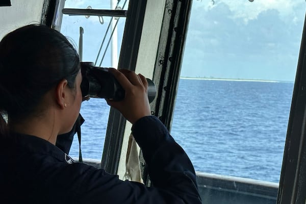 A member of the Philippine Navy uses binoculars as she looks at Northeast Cay, locally known as Parola Island, during a maritime patrol at the disputed South China Sea on Wednesday June 4, 2025. (AP Photo/Joeal Calupitan)