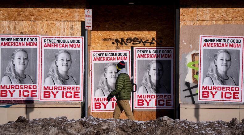A person walks past signage for Renee Good, who was fatally shot by an ICE officer earlier in the week, in Minneapolis, Minn., Sunday, Jan. 11, 2026. (Christopher Katsarov/The Canadian Press via AP)
