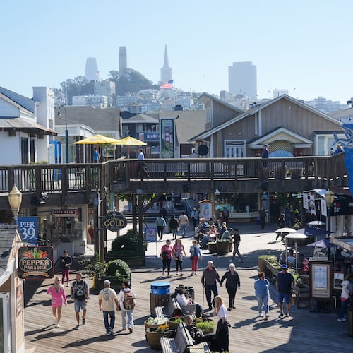 Visitors walk on the boardwalk at Fisherman's Wharf on Tuesday, Oct. 21, 2025, in San Francisco. (AP Photo/Jeff Chiu)