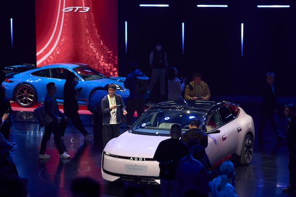 Attendees look at the latest cars from Volkswagen Group during the media night ahead of the Auto Show in Shanghai, Tuesday, April 22, 2025. (AP Photo/Ng Han Guan)