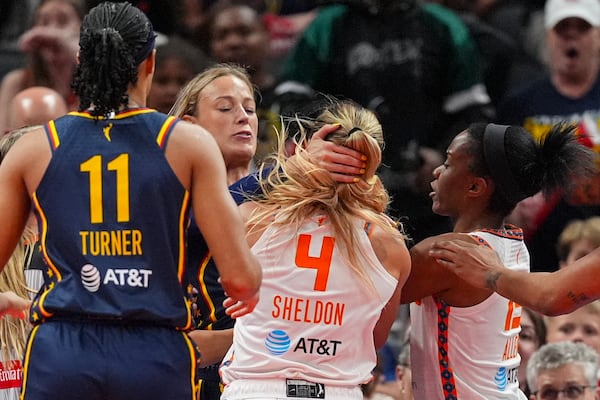 Indiana Fever guard Sophie Cunningham (8) and Connecticut Sun guard Jacy Sheldon (4) scuffle in the second half of a WNBA basketball game in Indianapolis, Tuesday, June 17, 2025. (AP Photo/Michael Conroy)